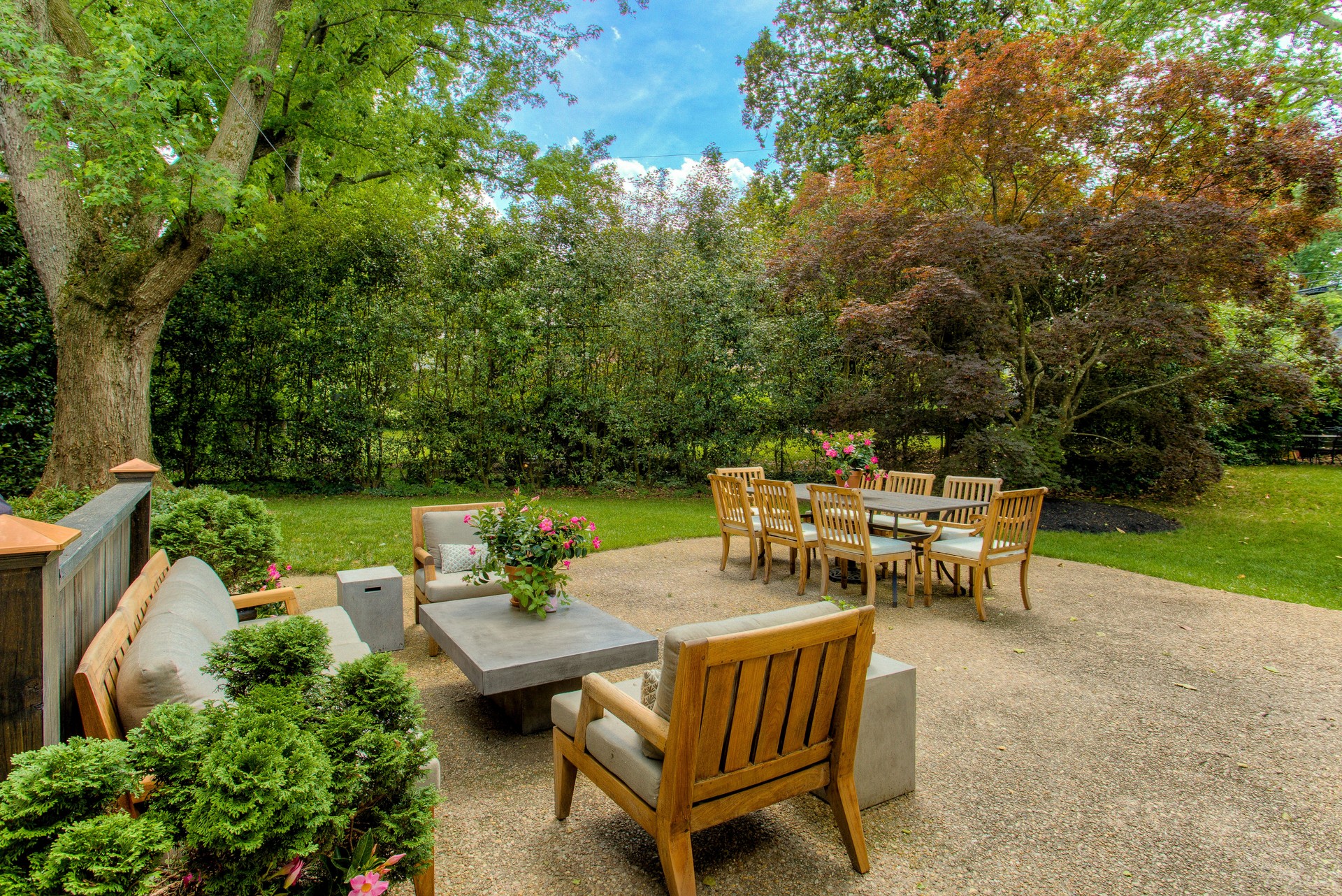 Outdoor Patio Area With Wooden Furniture Set Amid Lush Green Garden.